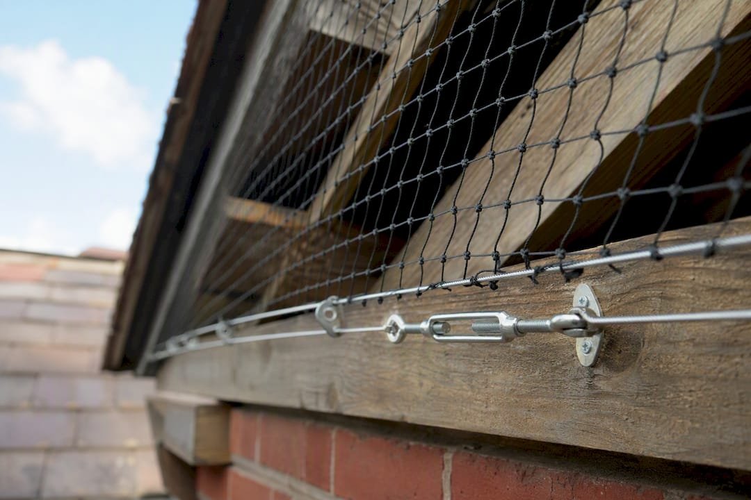 Close-up of taut black bird netting on roof eave