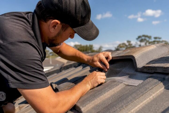 Licensed technician installing bird-proof mesh on roof vent