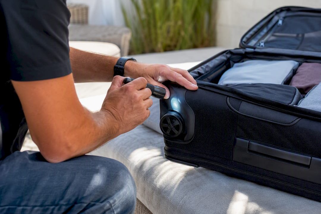 Hands inspecting suitcase seams with flashlight