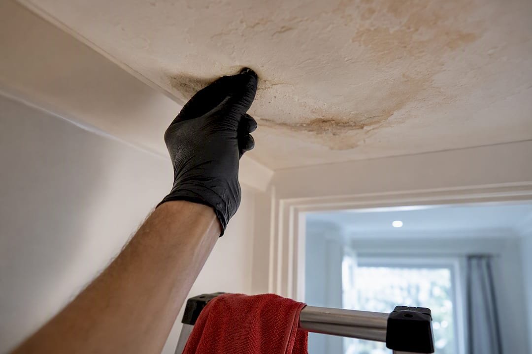 Gloved hand testing a soft ceiling patch