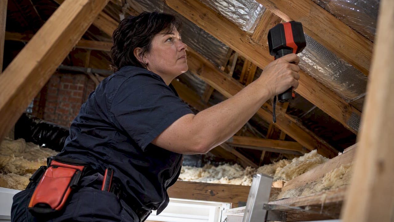 Technician using thermal camera in roof cavity