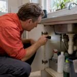 Homeowner inspecting under-sink cockroach hiding place