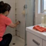 Mould spotting on bathroom grout beside separate cleaners