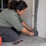Technician sealing a rat entry gap